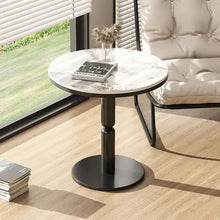 Round marble-top side table with black base in a living room setting.