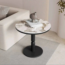 Round marble-top side table with a black base in a living room setting.